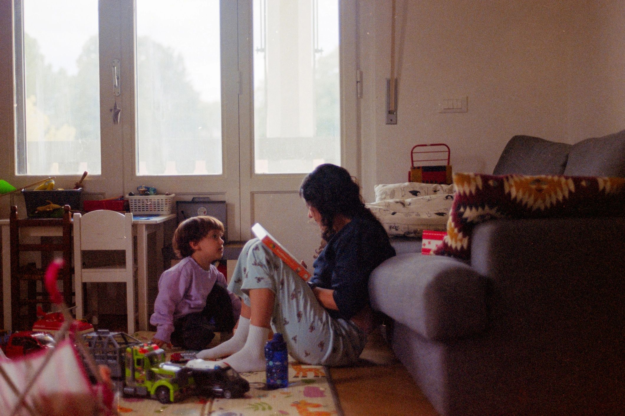 Mother reading book to child on floor at home